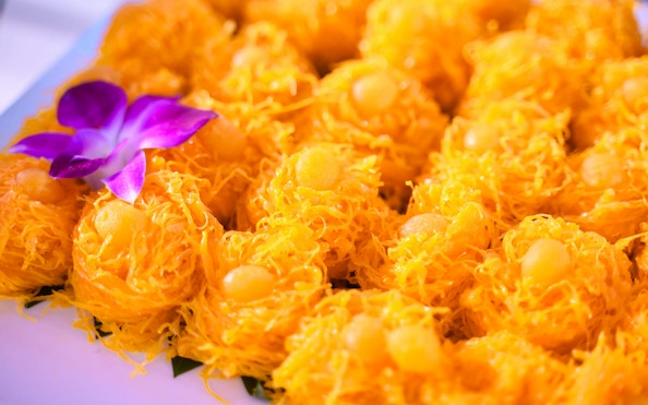 Golden desserts with purple orchid garnish on Smile Riverside Dinner Cruise buffet.