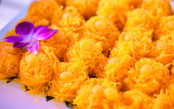 Golden desserts with purple orchid garnish on Smile Riverside Dinner Cruise buffet.