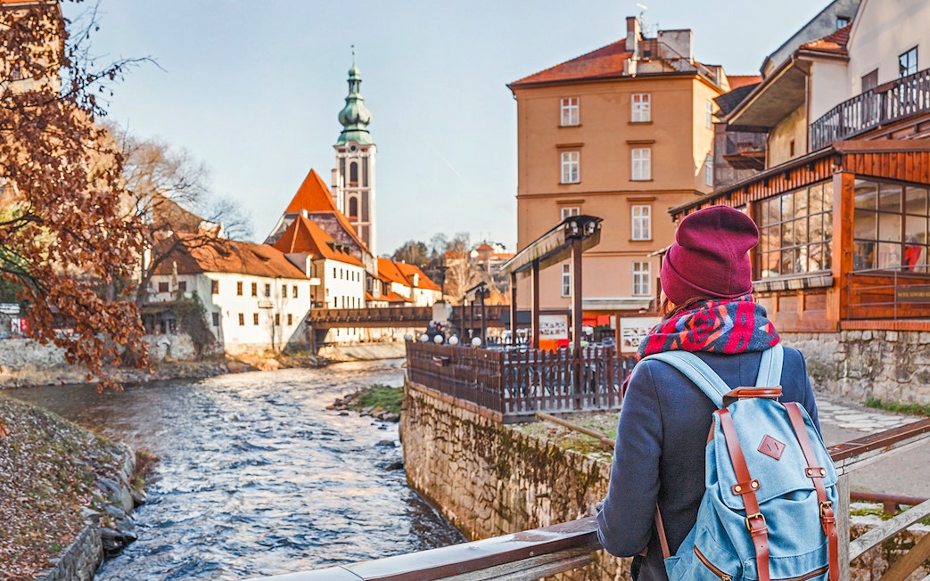 Cesky Krumlov visitor overlooking river and historic buildings with church tower in background.
