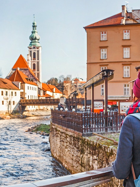 Cesky Krumlov visitor overlooking river and historic buildings with church tower in background.