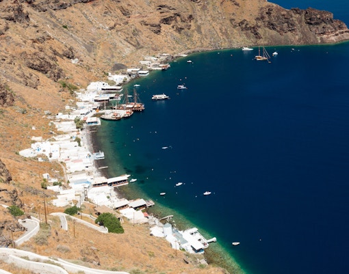 Aerial view of Manolas village coastline on Therasia island with boats in the bay.
