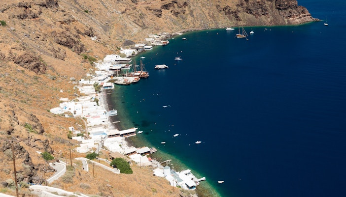 Aerial view of Manolas village coastline on Therasia island with boats in the bay.