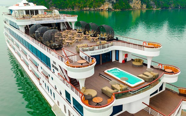 Aerial view of Ambassador cruise ship deck with seating and jacuzzi in scenic bay.