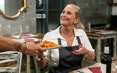 Woman receiving a plate of pasta during a cooking class in Trastevere, Rome.