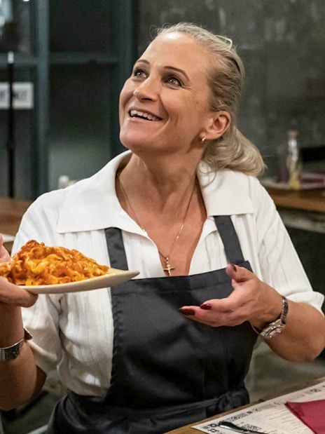 Woman receiving a plate of pasta during a cooking class in Trastevere, Rome.