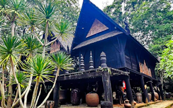 Traditional wooden house surrounded by lush greenery in Chiang Rai, part of the 2-Day Doi Chang tour.