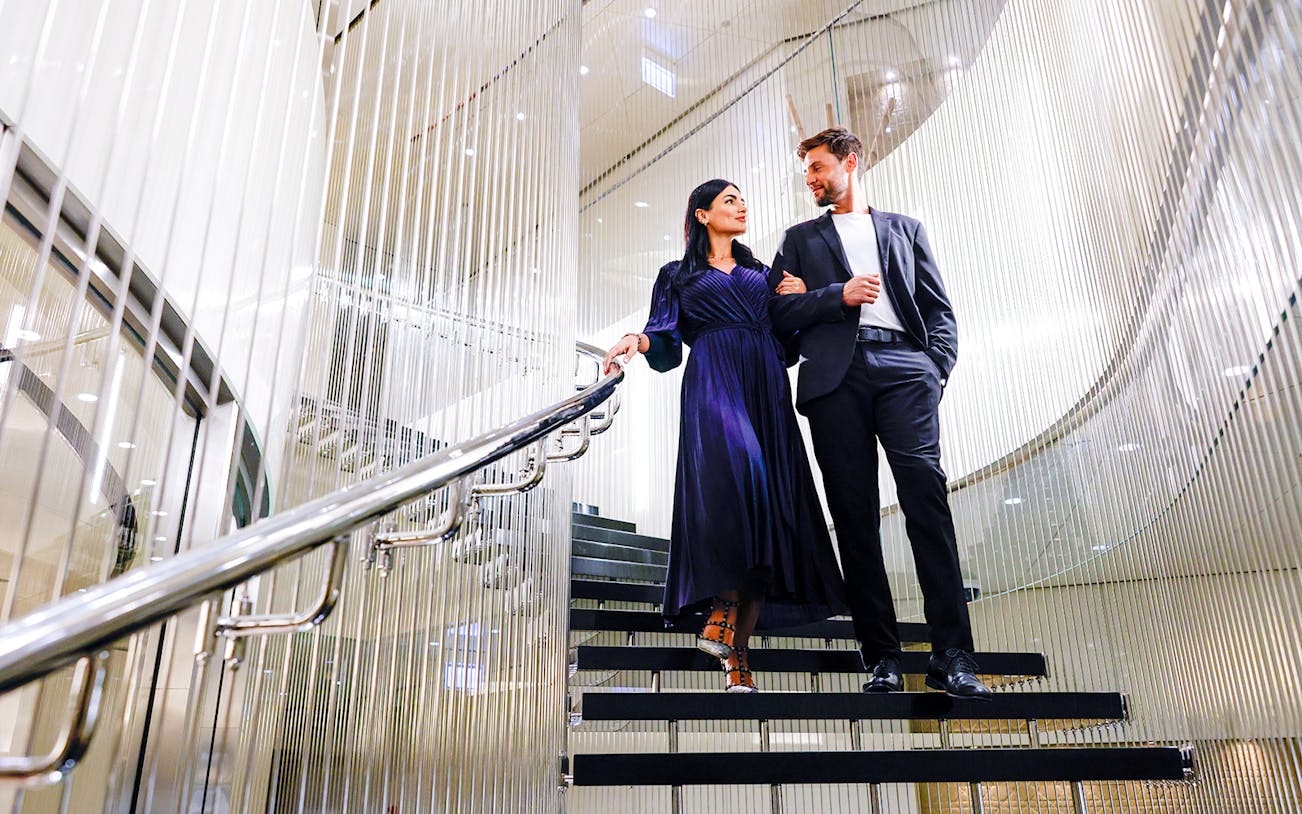 Couple walking down elegant staircase at Burj Khalifa Level 152 Lounge.