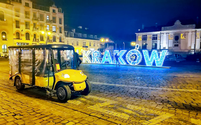 Golf cart in Krakow Old Town at night with illuminated sign.