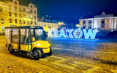 Golf cart in Krakow Old Town at night with illuminated sign.