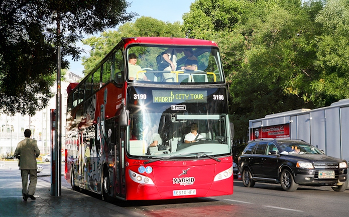 Red double-decker bus for Madrid Hop On Hop Off tour parked on a city street.