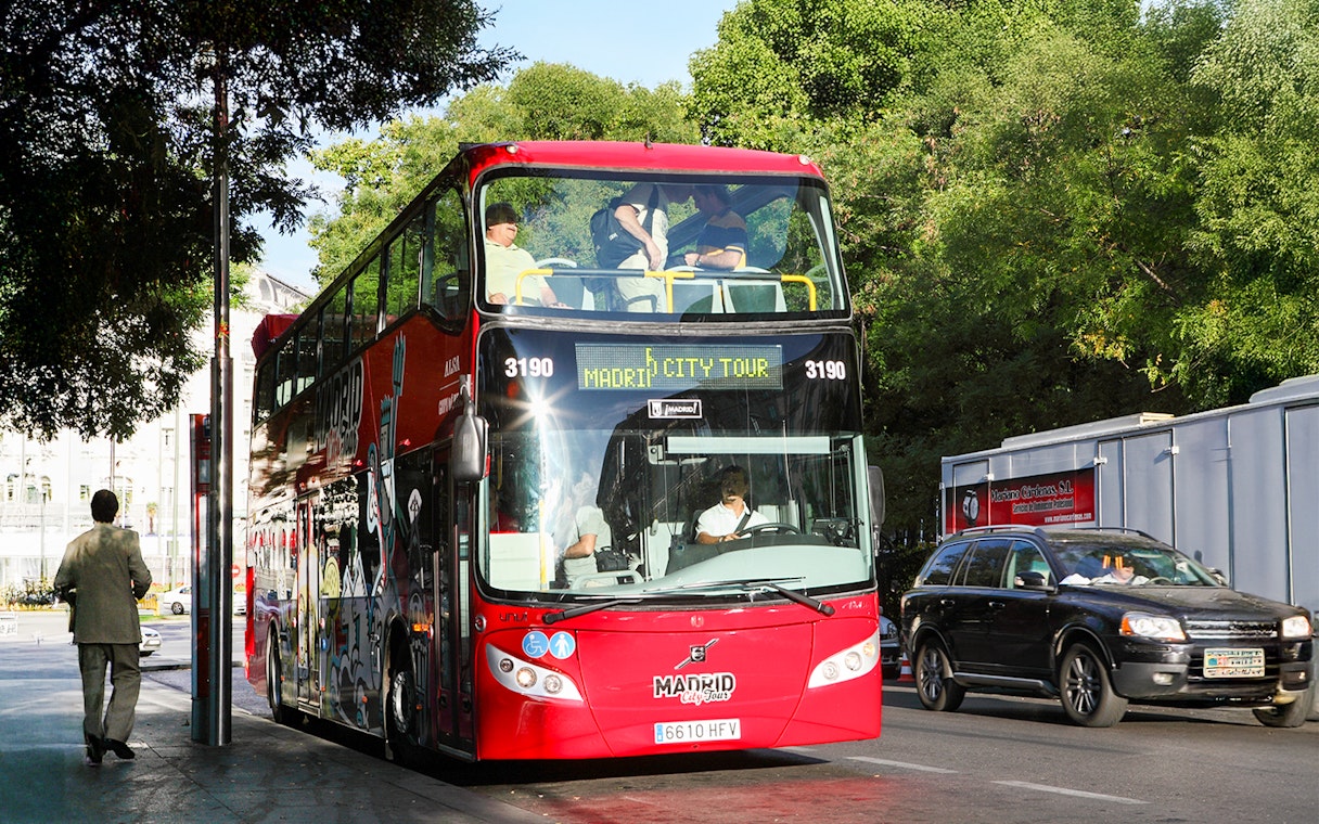 Red double-decker bus for Madrid Hop On Hop Off tour parked on a city street.