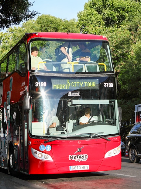 Red double-decker bus for Madrid Hop On Hop Off tour parked on a city street.
