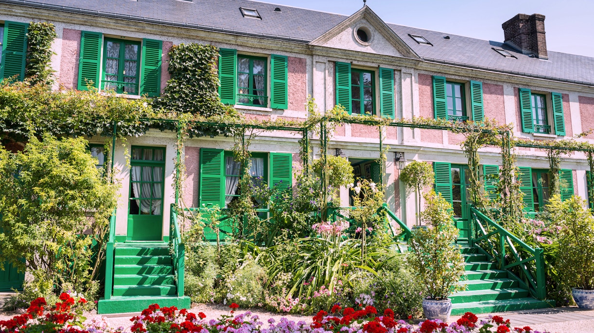 Giverny garden with The Artist's House surrounded by vibrant flowers and lush greenery.