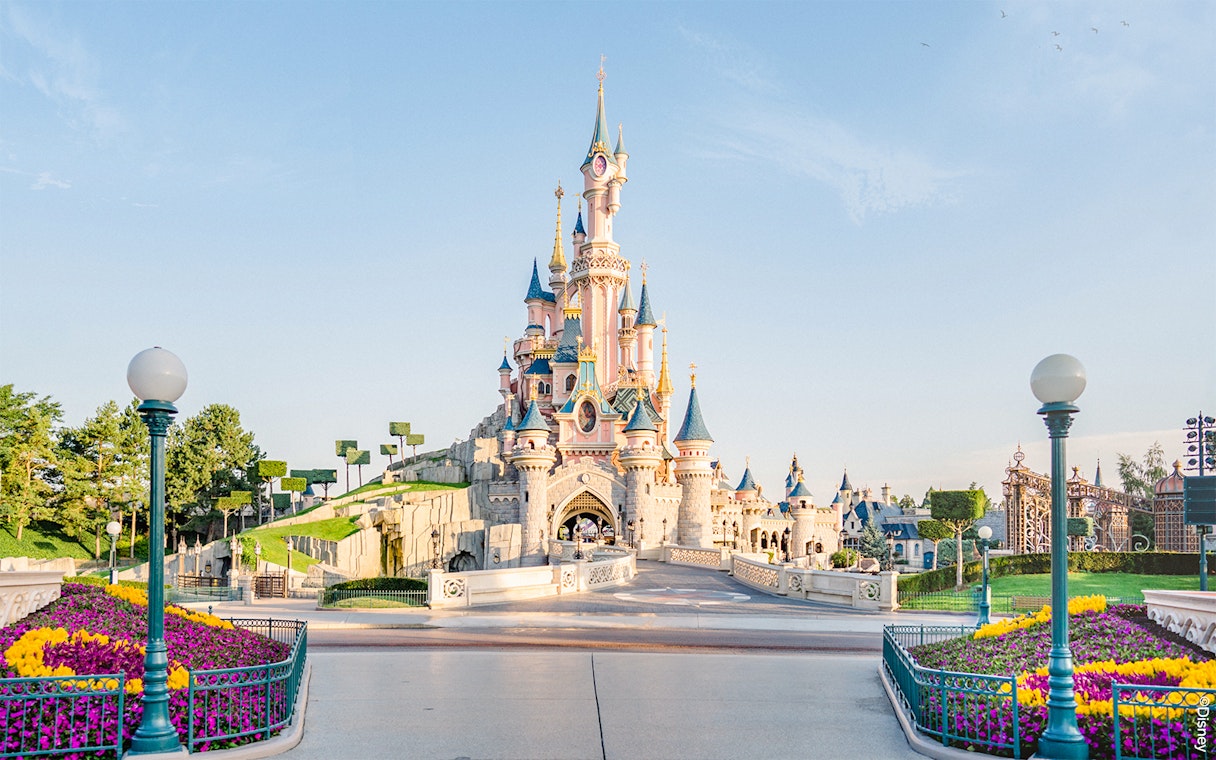 Sleeping Beauty Castle at Disneyland Paris with colorful flower beds.