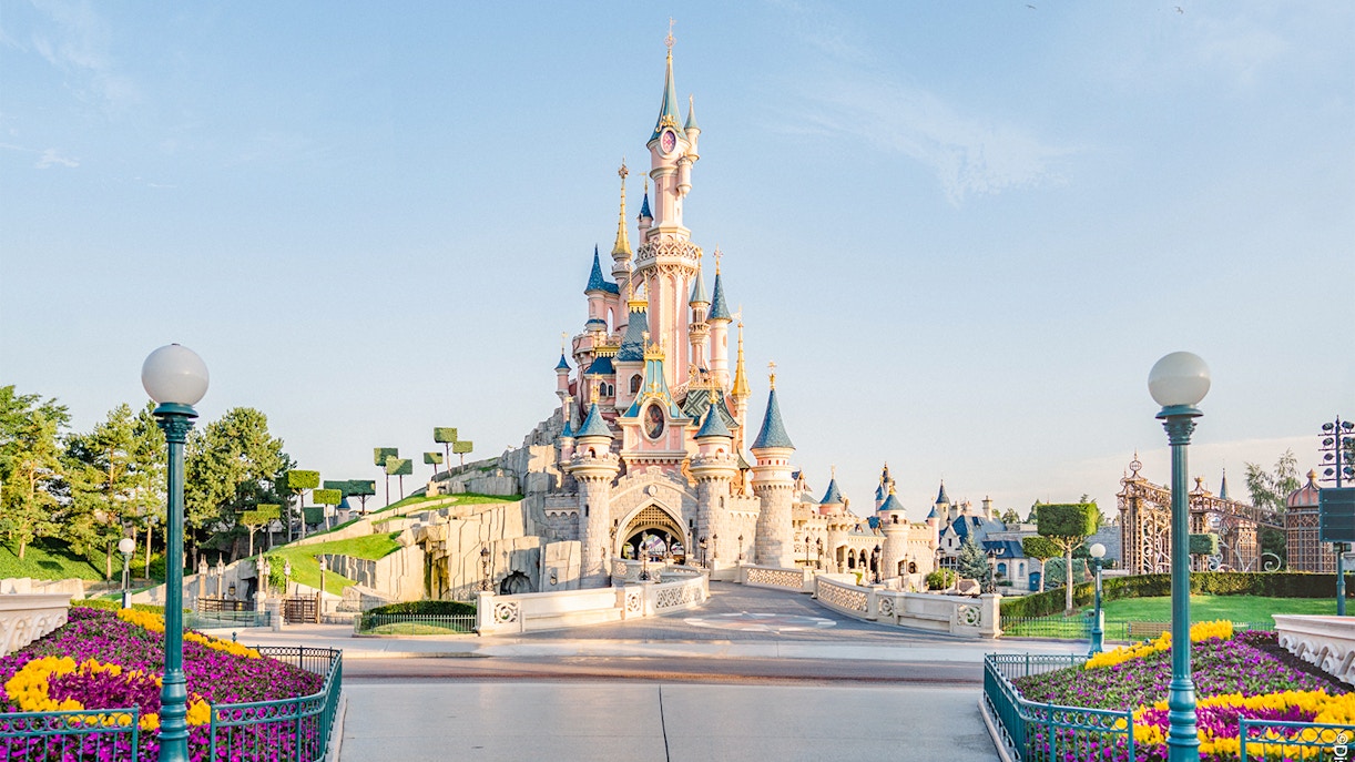 Sleeping Beauty Castle at Disneyland Paris with colorful flower beds.