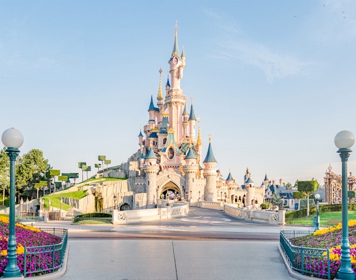 Sleeping Beauty Castle at Disneyland Paris with colorful flower beds.