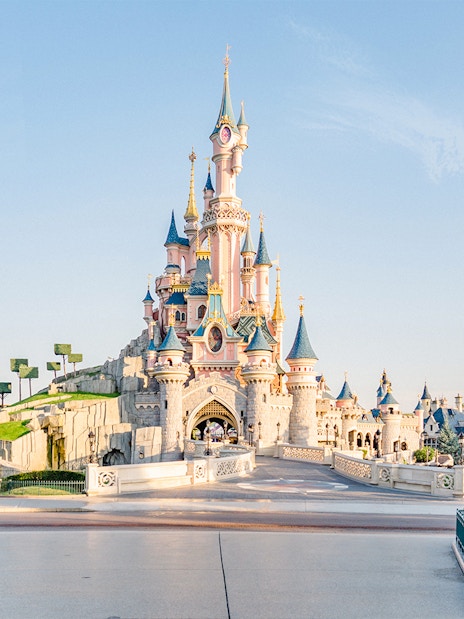 Sleeping Beauty Castle at Disneyland Paris with colorful flower beds.