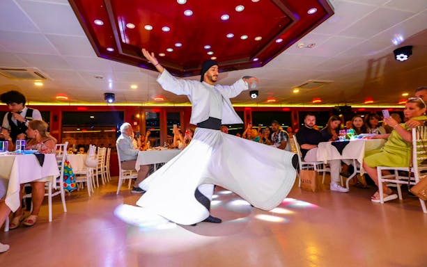 Dervish dancer performing on Bosphorus dinner cruise with guests dining.