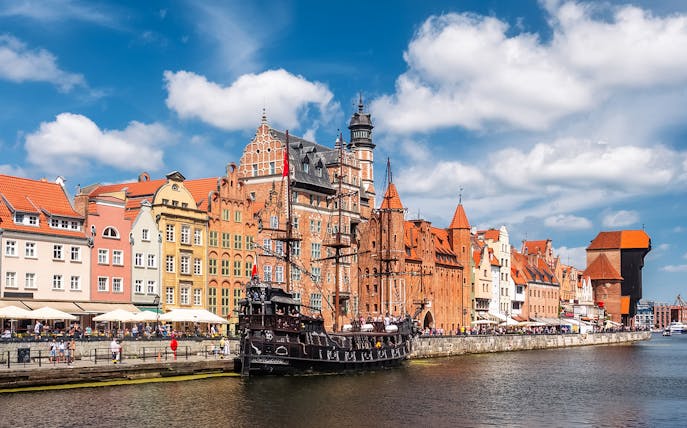 Gdansk old town buildings along the Motlawa River with a historic ship docked.
