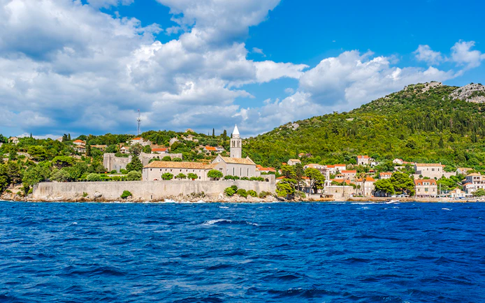 Elaphiti Islands view from boat tour, Dubrovnik, showing coastal village and church.