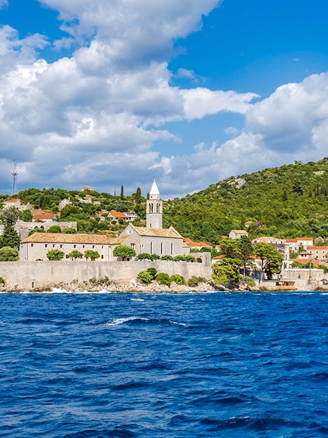 Elaphiti Islands view from boat tour, Dubrovnik, showing coastal village and church.