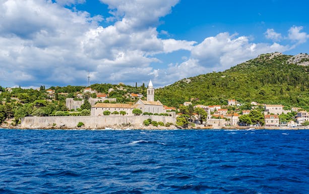 Elaphiti Islands view from boat tour, Dubrovnik, showing coastal village and church.