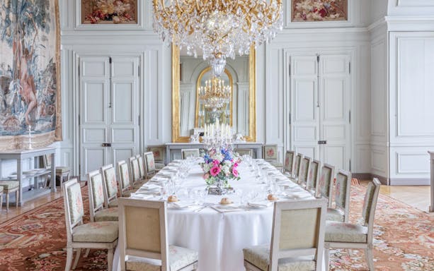 Dining room with ornate chandelier and long table set for a banquet, Castle of Rambouillet.