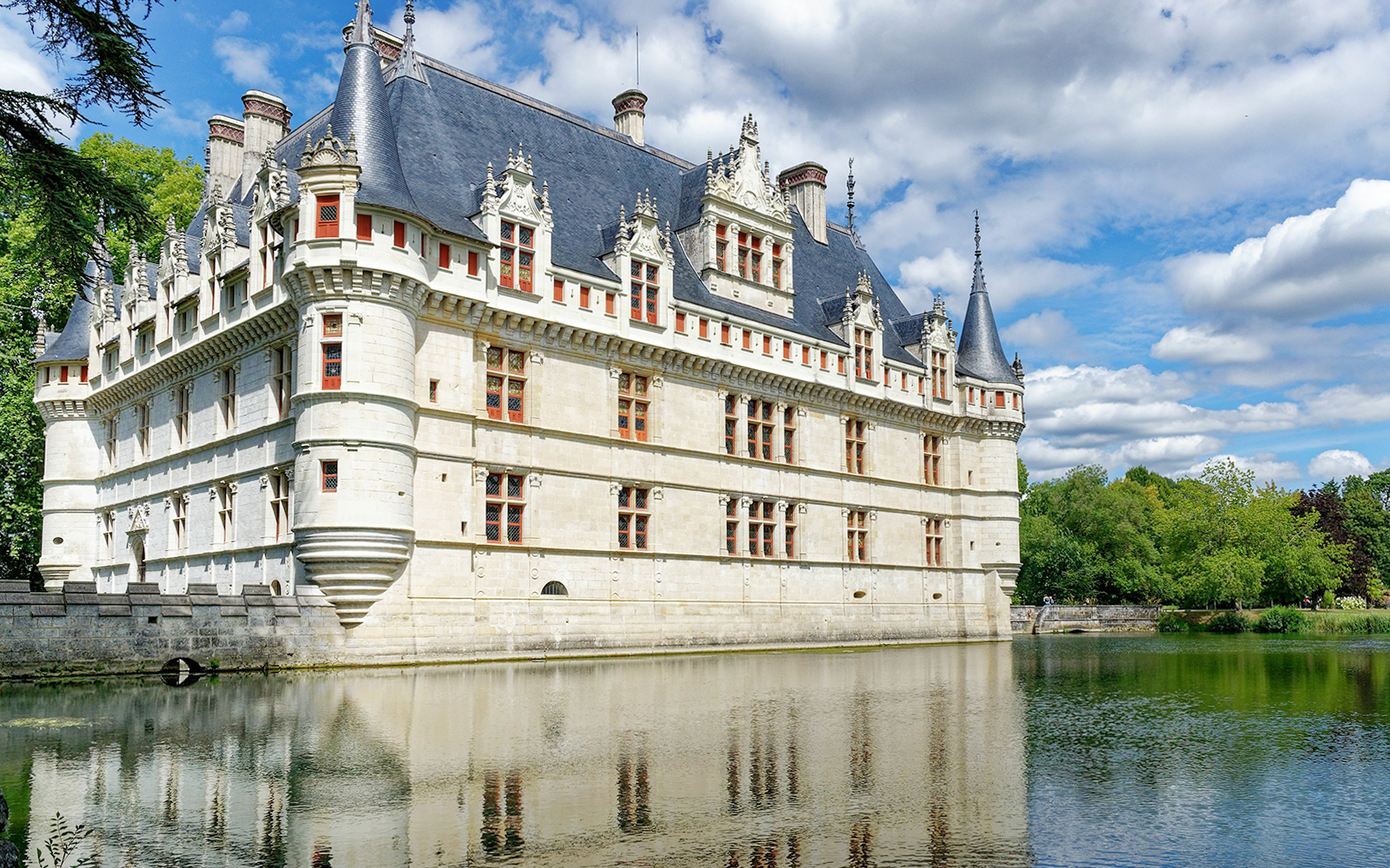 Azay le Rideau Castle reflecting in a calm river under a blue sky.