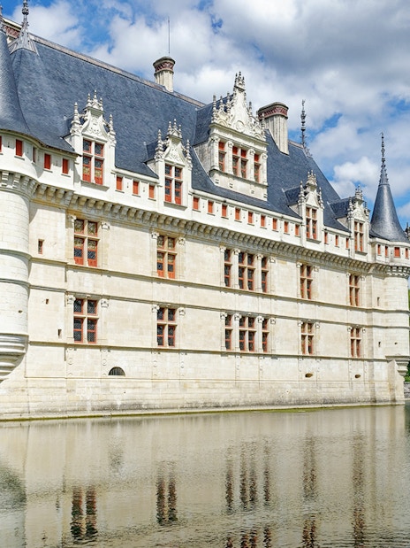 Azay le Rideau Castle reflecting in a calm river under a blue sky.