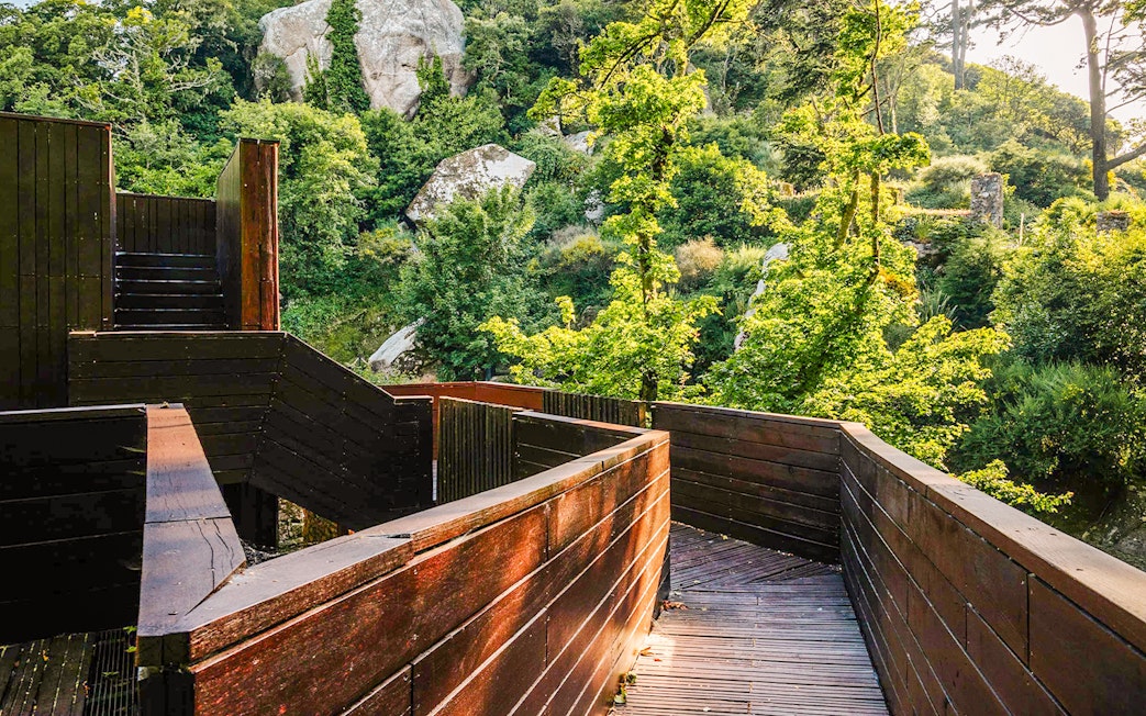 Walkway through lush greenery at Moorish Castle former stables, Sintra, Portugal.
