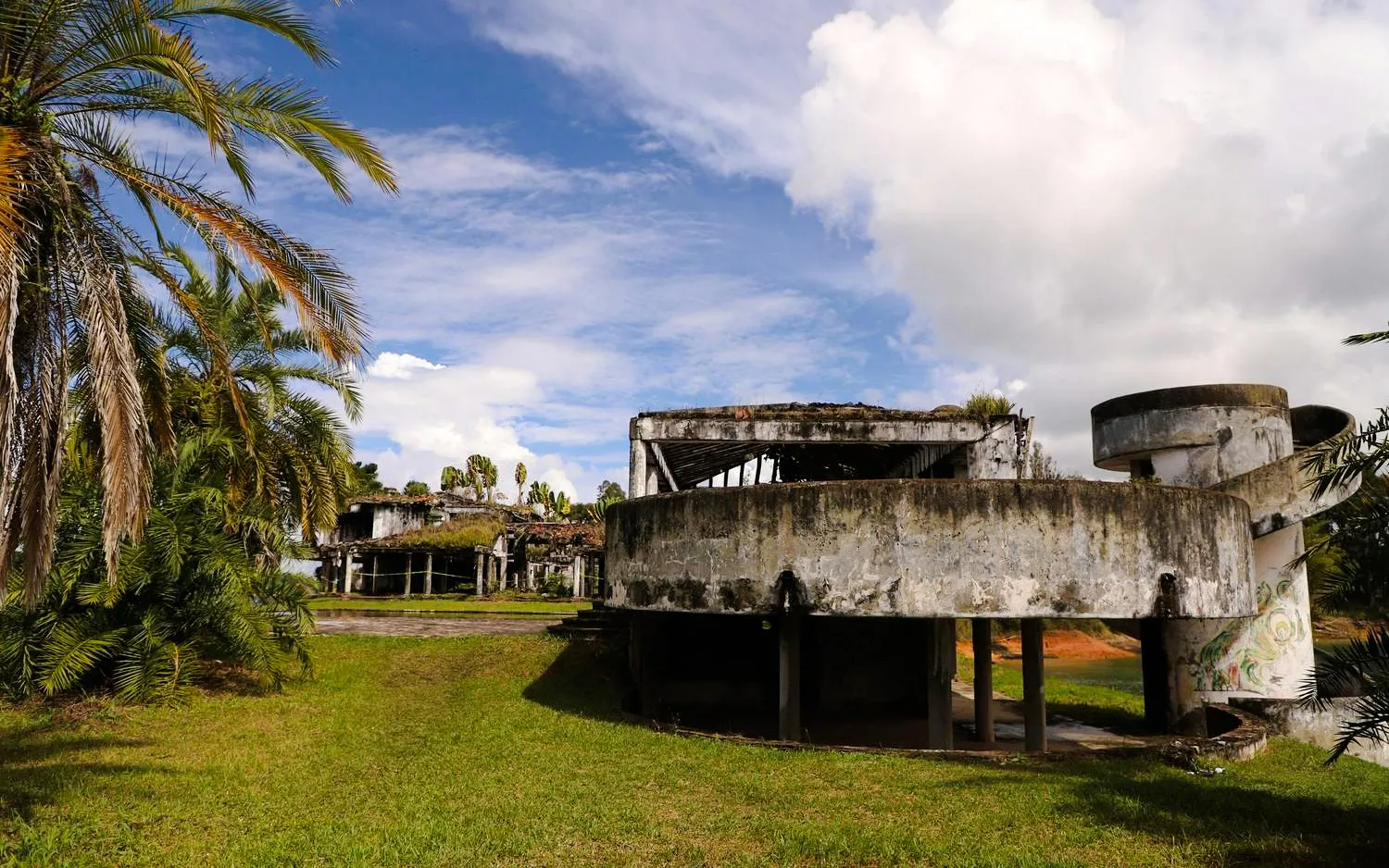 Ruins of La Manuela mansion by Pablo Escobar, Guatapé, Colombia, with palm trees and blue sky.