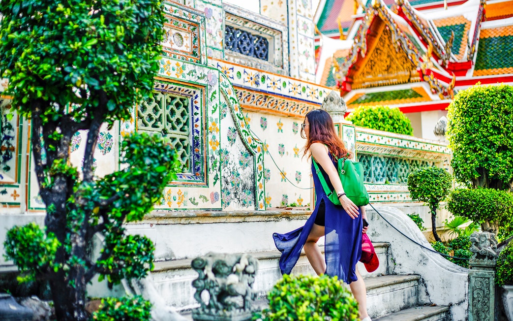 Woman climbing steps at Wat Arun temple, Bangkok.