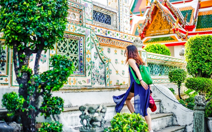 Woman climbing steps at Wat Arun temple, Bangkok.