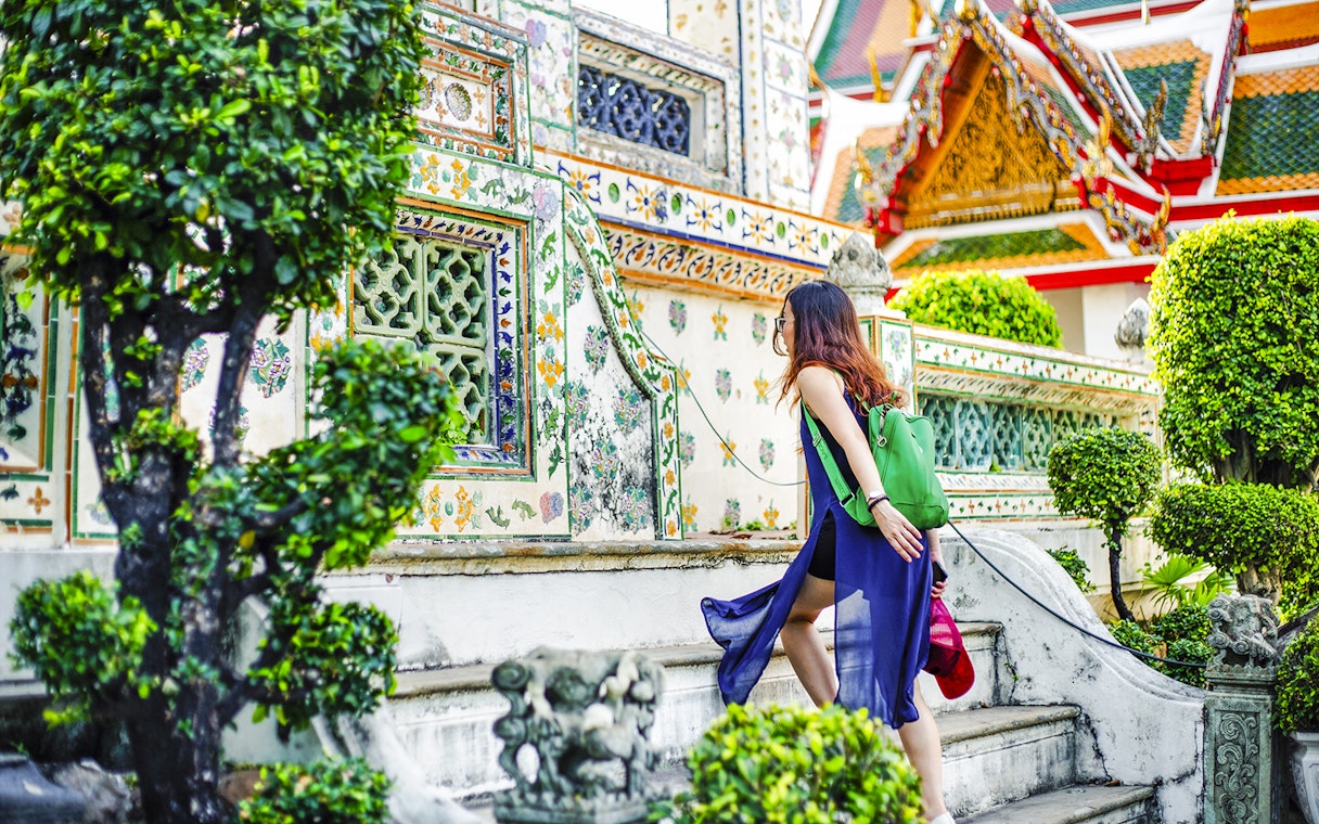Woman climbing steps at Wat Arun temple, Bangkok.