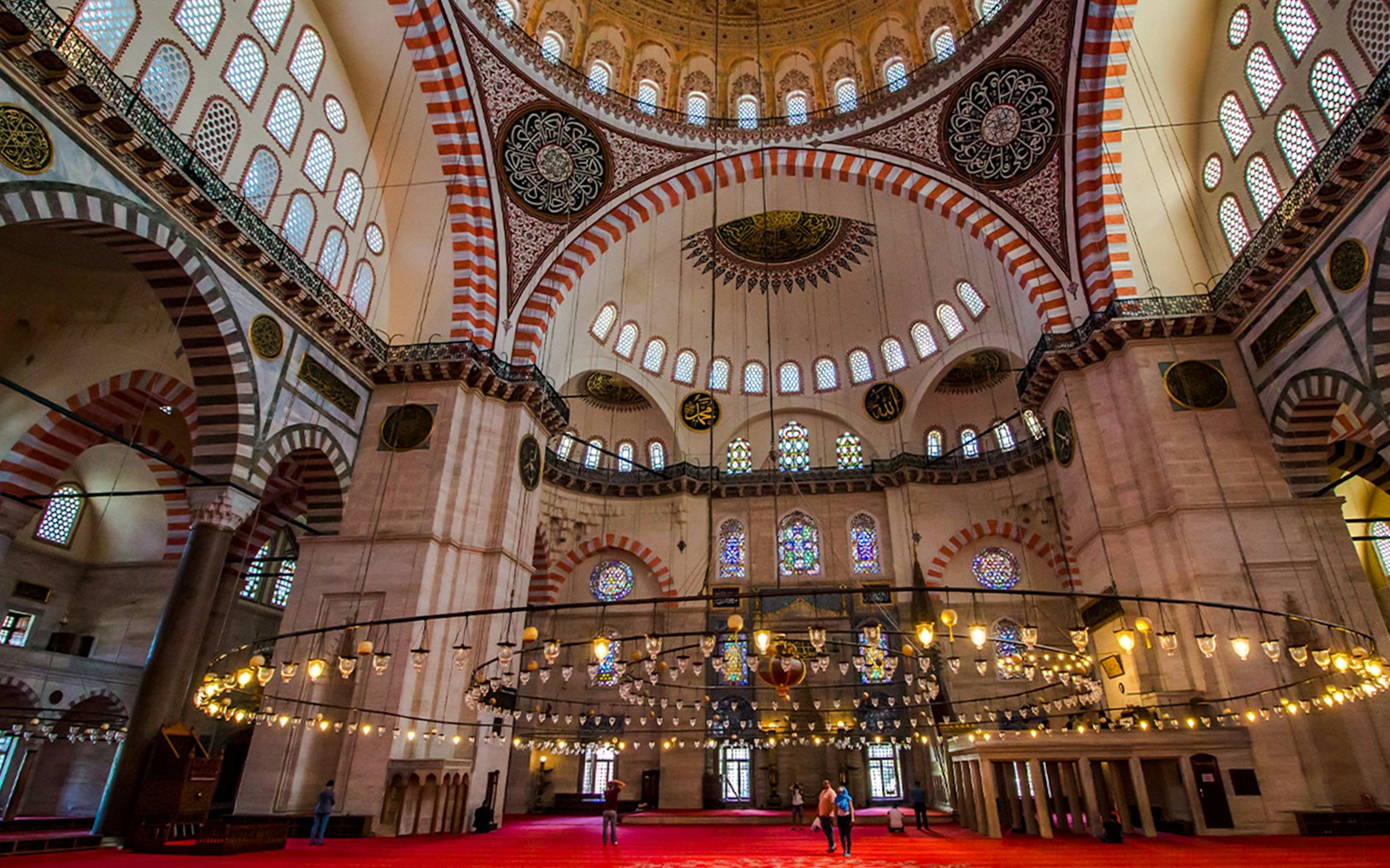 Süleymaniye Mosque interior with ornate dome ceiling and stained glass windows.