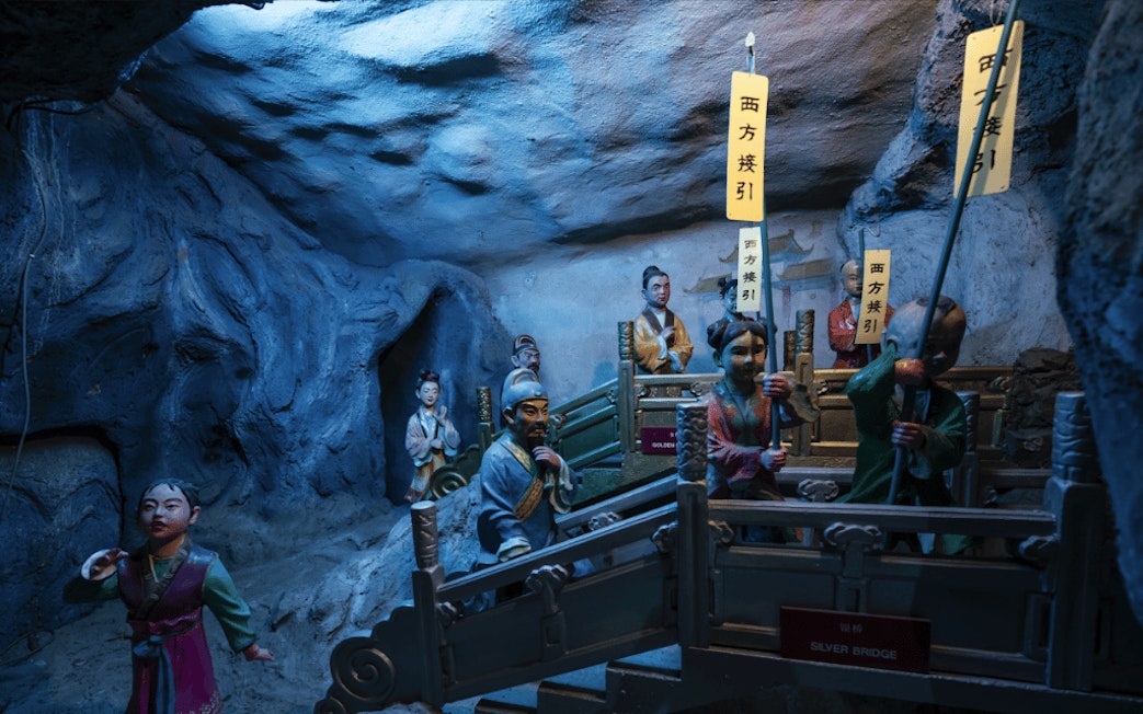 Diorama of figures crossing the Silver Bridge at Hell's Museum, depicting an afterlife scene.