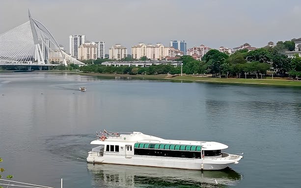 Cruise boat on Tasik Putrajaya with city skyline and bridge in the background.