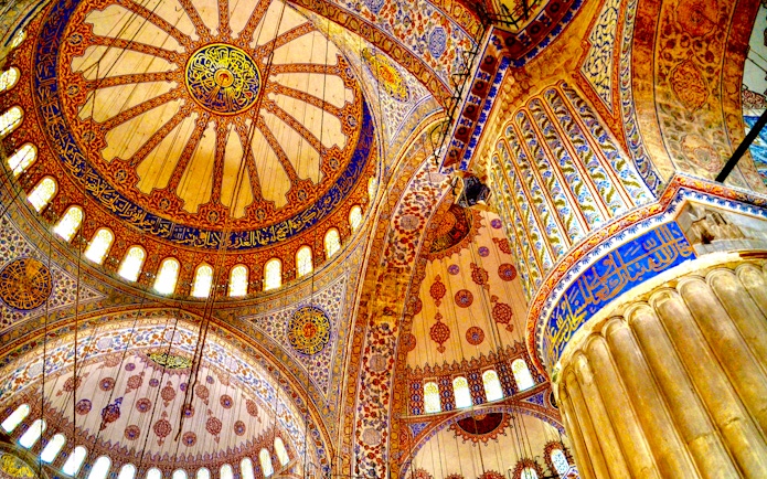 Ceiling of the Blue Mosque in Istanbul with intricate patterns and Arabic calligraphy.