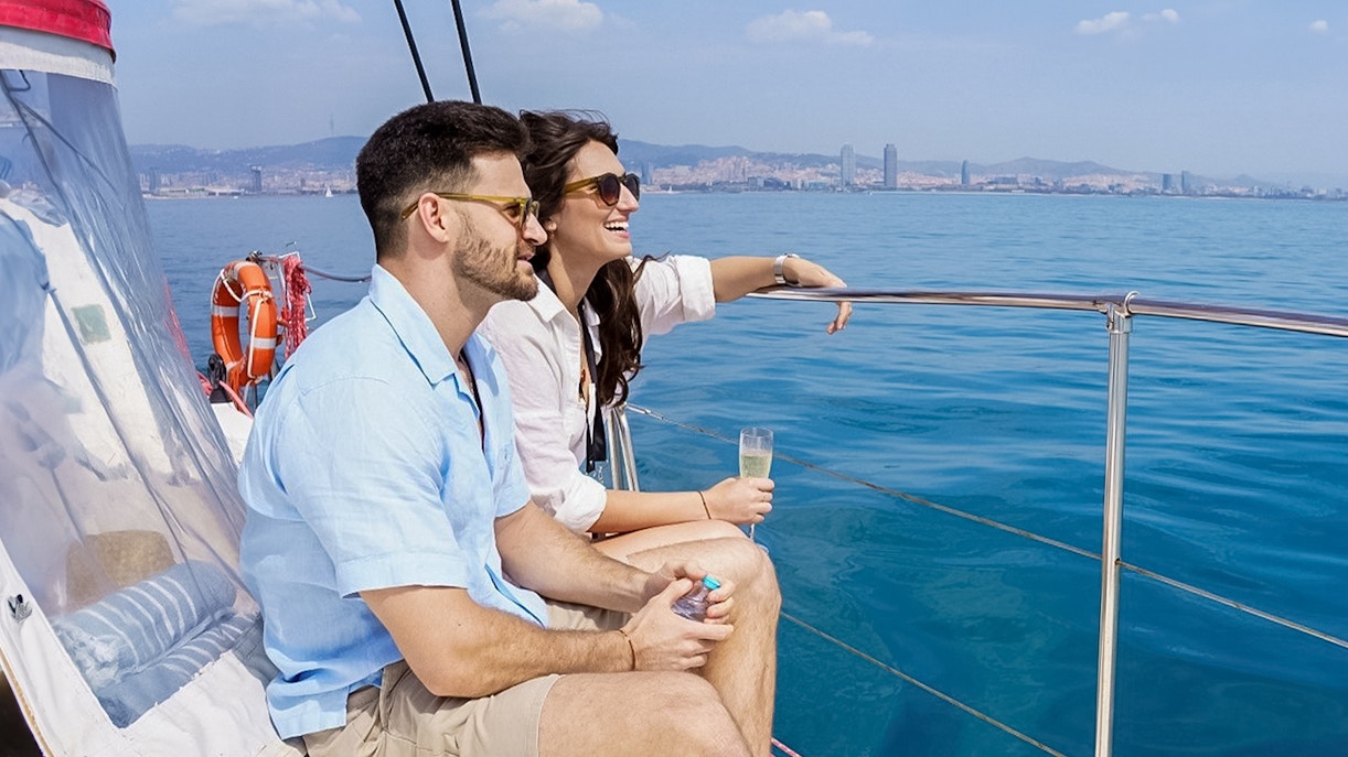 Couple enjoying champagne on a Barcelona cruise with city skyline in the background.