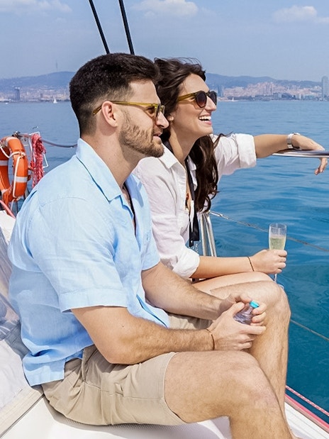 Couple enjoying champagne on a Barcelona cruise with city skyline in the background.