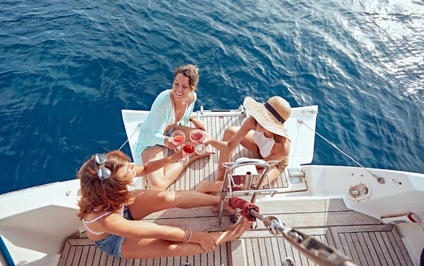 Group enjoying drinks on a boat deck during Alghero Bay tour from Fertilia.