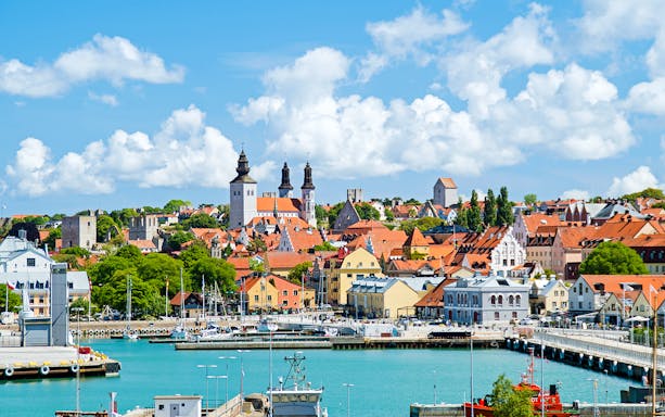 Visby harbor with medieval buildings and church towers in the background.