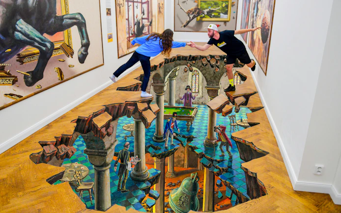 Visitors interacting with 3D floor art at IAM Illusion Art Museum, Prague.
