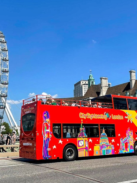 Red double-decker bus near the London Eye on the Thames River cruise tour.