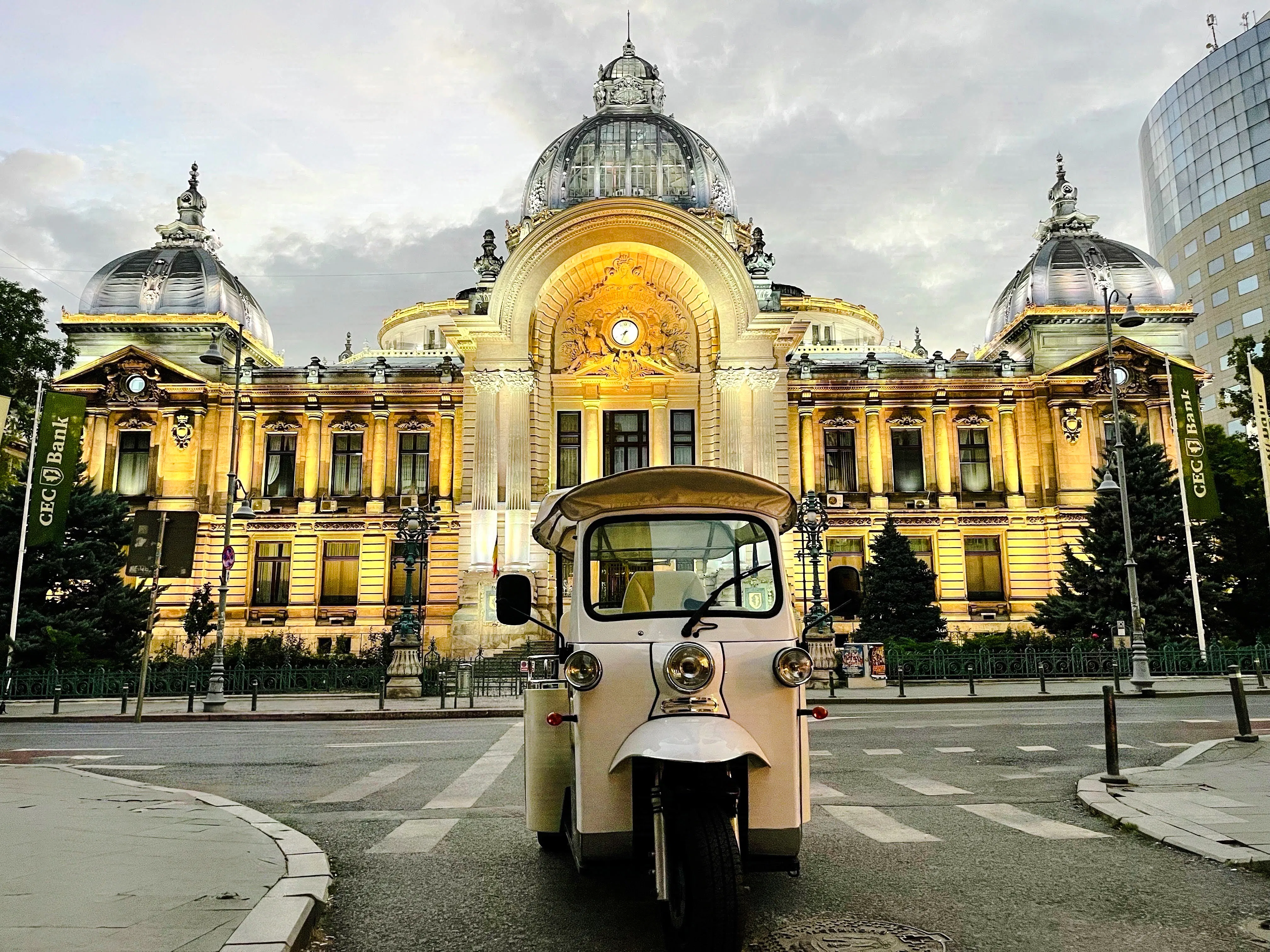 Tuk Tuk in front of illuminated CEC Palace, Bucharest, during highlights tour.