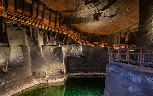 Wieliczka Salt Mine chamber with wooden walkways and green water.
