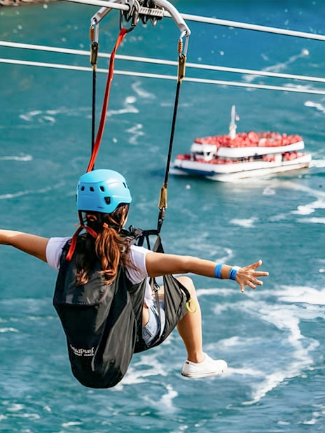 Person ziplining over water with a boat below at Niagara Falls.