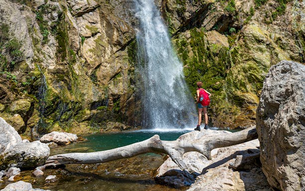 Person standing by a waterfall in Varziela River, Castro Laboreiro during guided canyoning tour.