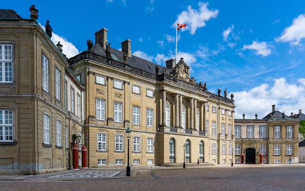 Amalienborg Castle Square in Copenhagen with historic architecture and Danish flag.