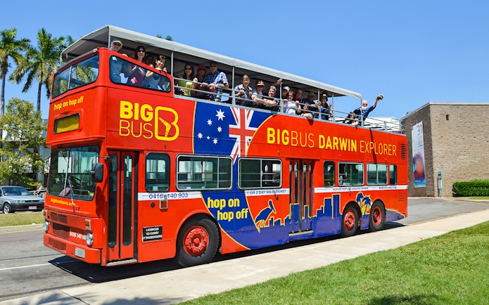 Open-top red bus with tourists on a Darwin city tour.